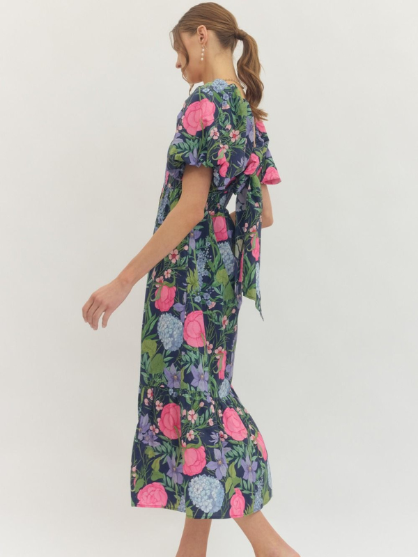 Woman wearing a floral dress with pink, blue, and green flowers on a white background