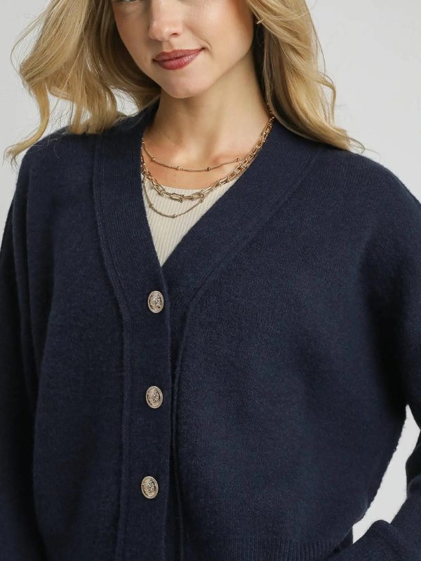 Navy cardigan with button details worn by a person, on a neutral background