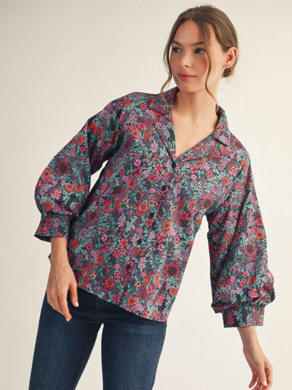 Woman wearing a floral blouse with long sleeves on a plain background