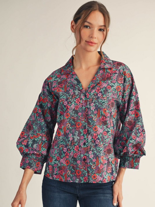 Woman wearing a floral blouse with long sleeves on a plain background