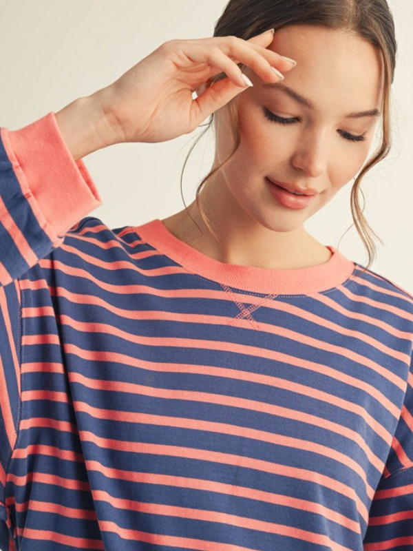 Woman wearing a blue and pink striped shirt with a neutral background