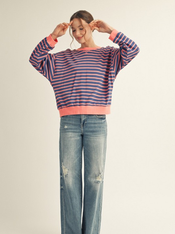Person wearing a striped sweater and jeans on a plain background