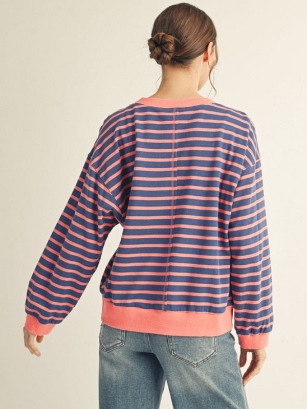 Person wearing a striped sweater with pink and blue horizontal stripes on a beige background