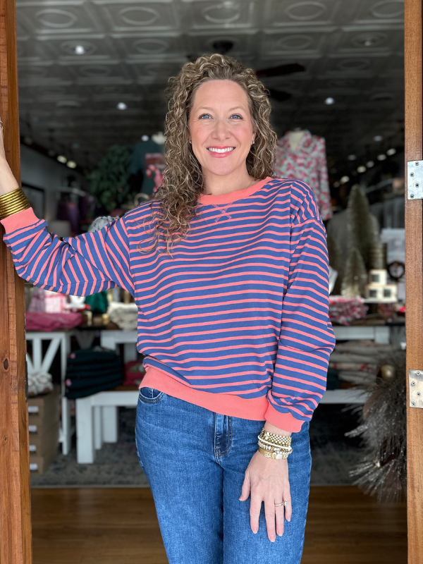 Woman wearing a striped sweater and jeans standing inside a store.