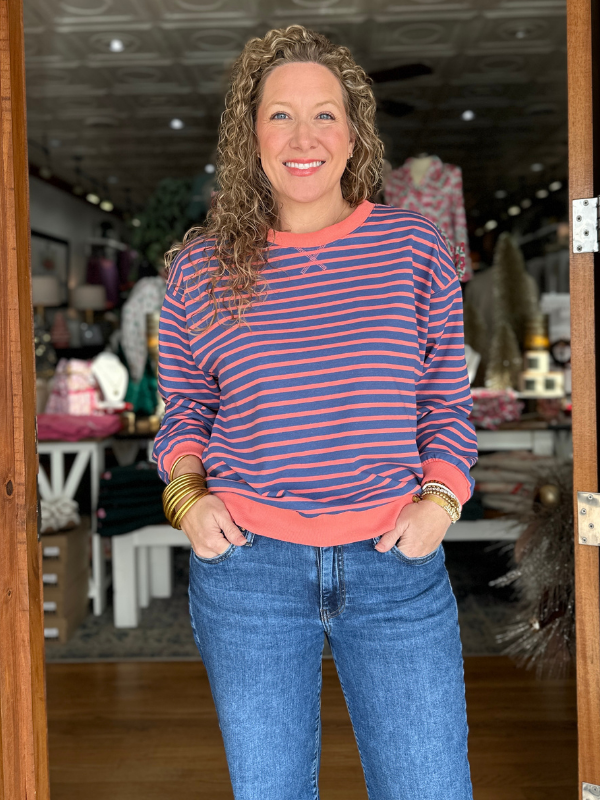 Woman wearing a striped sweater and jeans standing inside a store.
