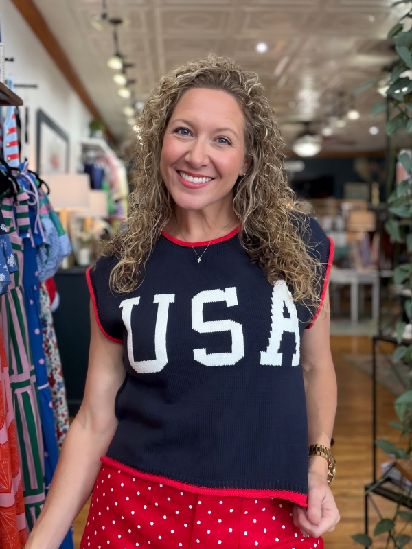Woman wearing a black sleeveless top with 'USA' text in a store setting