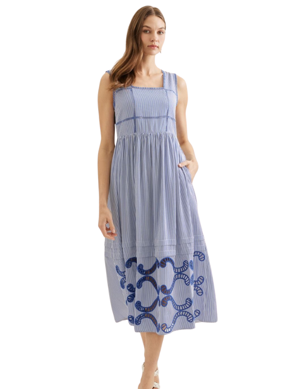 Woman wearing a blue and white striped dress with embroidery on a white background