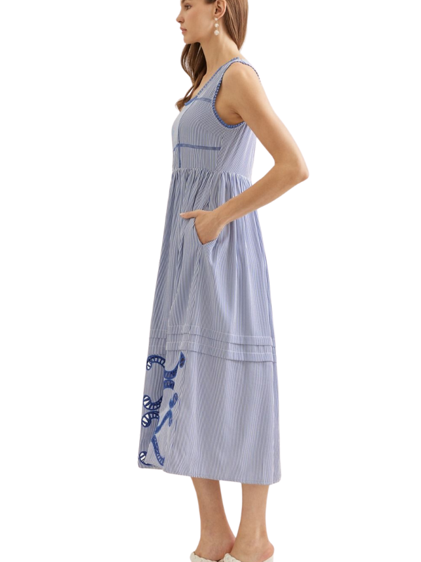 Woman wearing a blue and white striped dress with an embroidered design on a white background