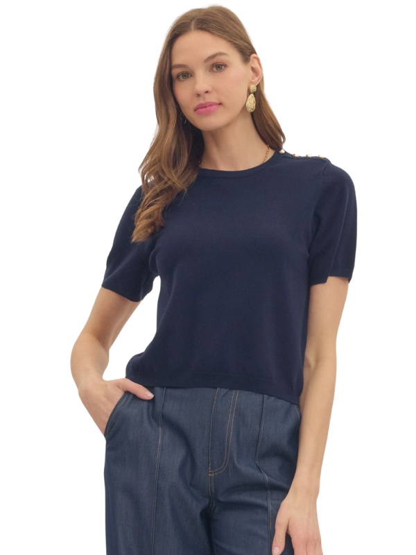 Woman wearing a navy blue top and dark pants on a white background