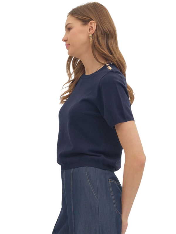 Woman wearing a navy blue top and denim skirt on a white background