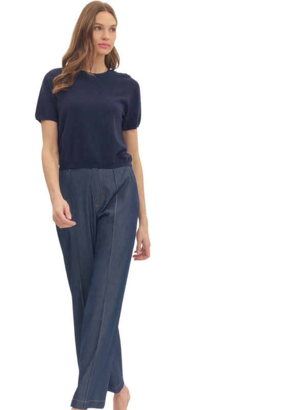 Woman wearing a navy top and gray pants on a white background
