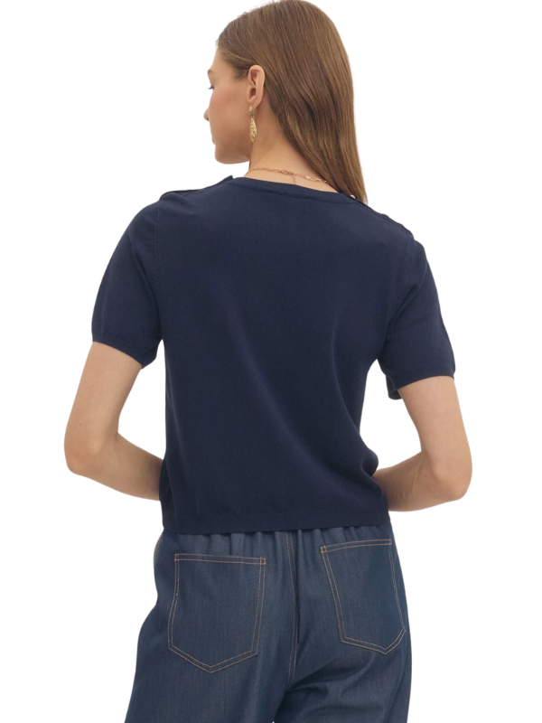 Person wearing a navy blue t-shirt and denim pants on a white background