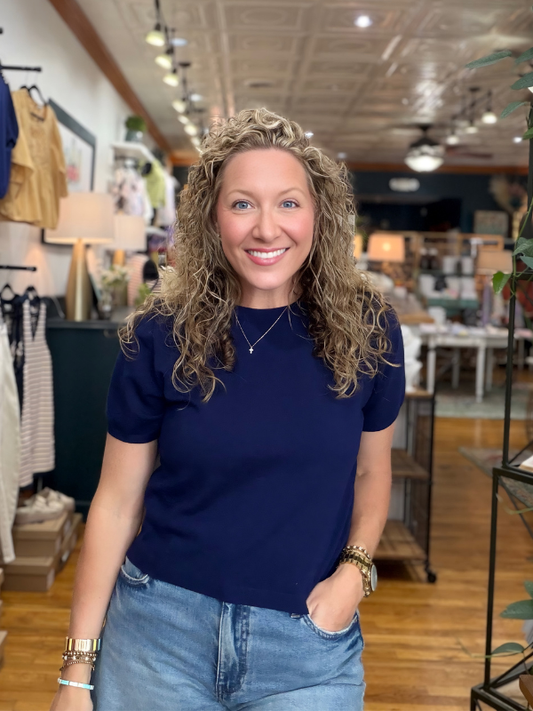 Woman in a navy blue shirt and jeans standing in a store.
