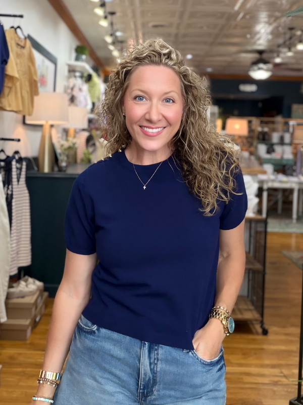 Woman wearing a navy blue t-shirt and jeans standing in a store.