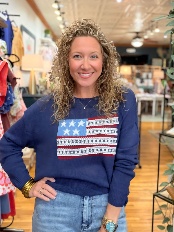 Woman wearing a blue sweatshirt with an American flag design in a store setting