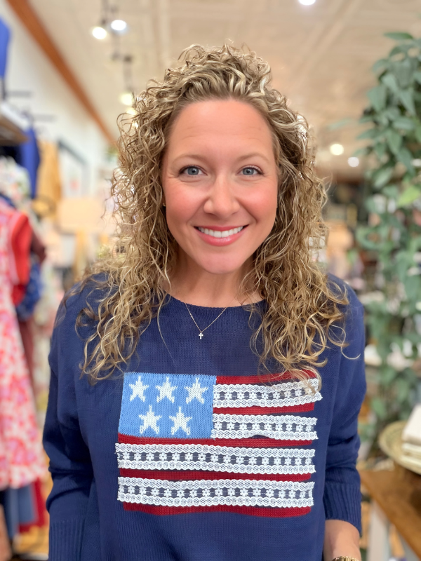 Woman wearing a blue sweater with an American flag design in a store setting