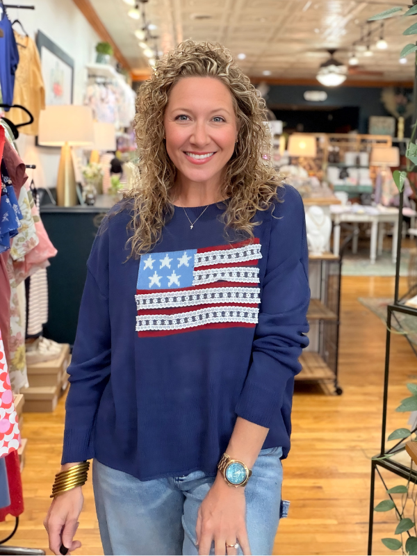 Woman wearing a blue sweater with an American flag design in a store setting