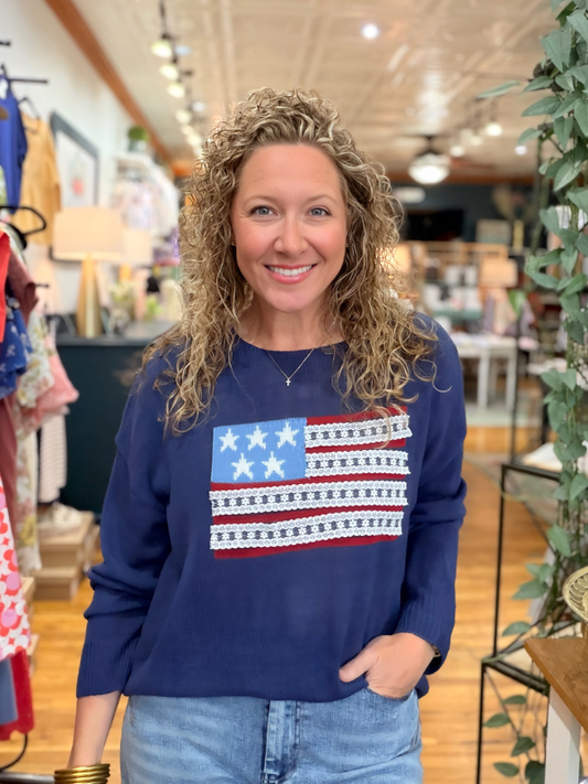 Woman wearing a blue sweatshirt with an American flag design in a store setting
