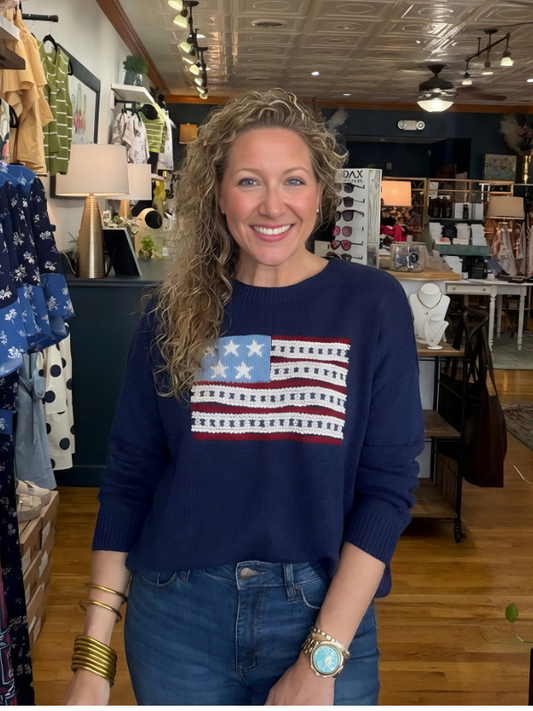 Woman wearing a navy sweater with an American flag design in a store setting