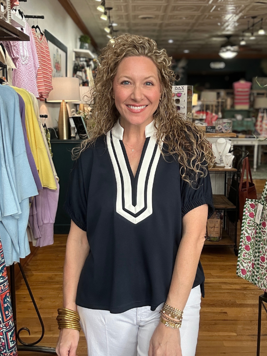 Woman wearing a black top with a white collar in a clothing store.