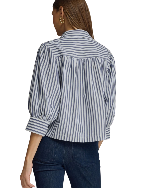 A woman shown from the back wearing a cropped long-sleeve blouse with vertical navy and white stripes, paired with dark blue jeans, against a plain white background.