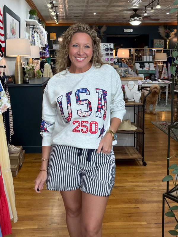 Woman wearing a 'USA 250' sweatshirt in a store setting