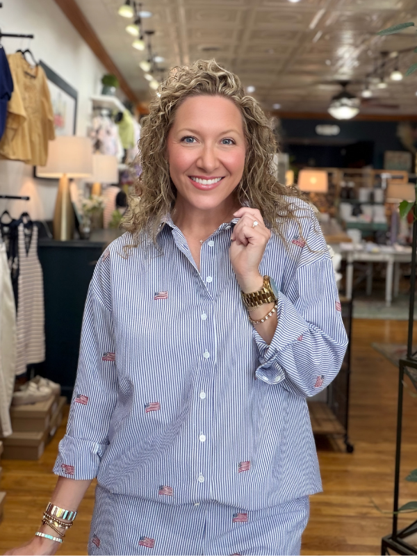 Woman wearing a blue striped shirt with small flags in a store setting