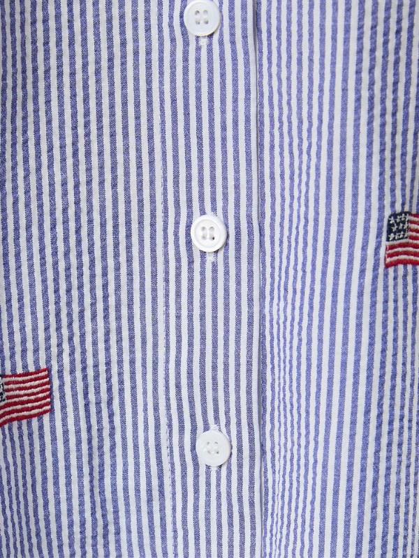 Close-up of a blue and white striped shirt with button details and American flag patch.