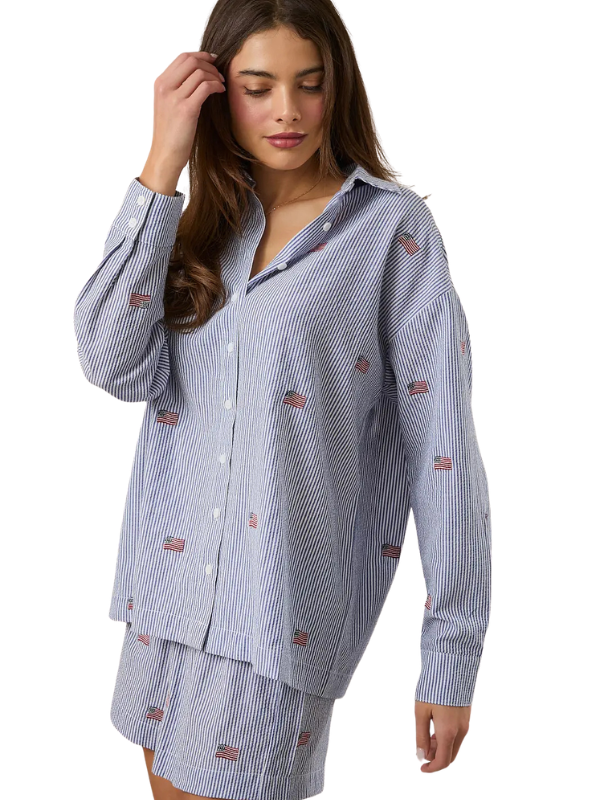 Woman wearing a blue striped pajama set with small flags on a white background