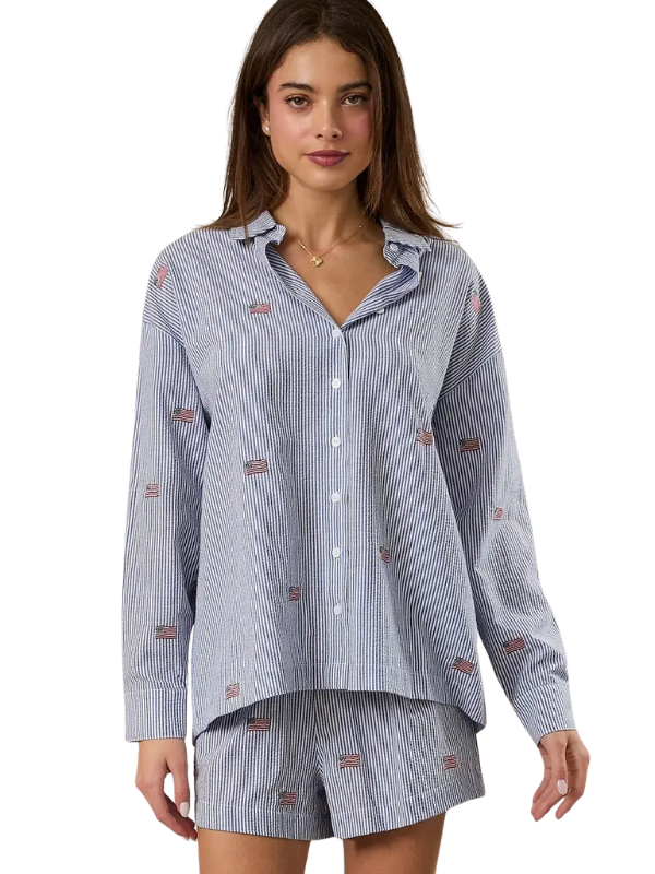 Woman wearing a blue striped pajama set with small red and gold designs on a white background
