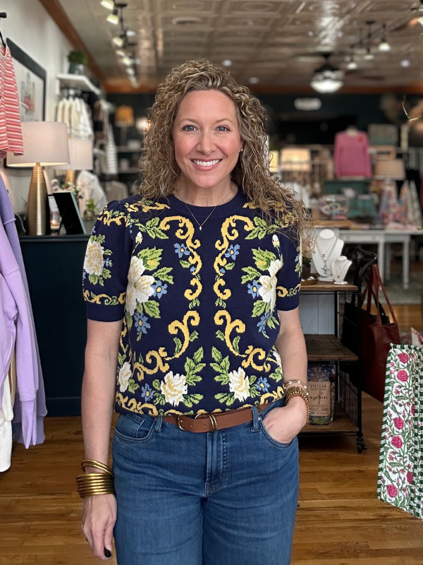 Woman wearing a patterned top and jeans in a store setting