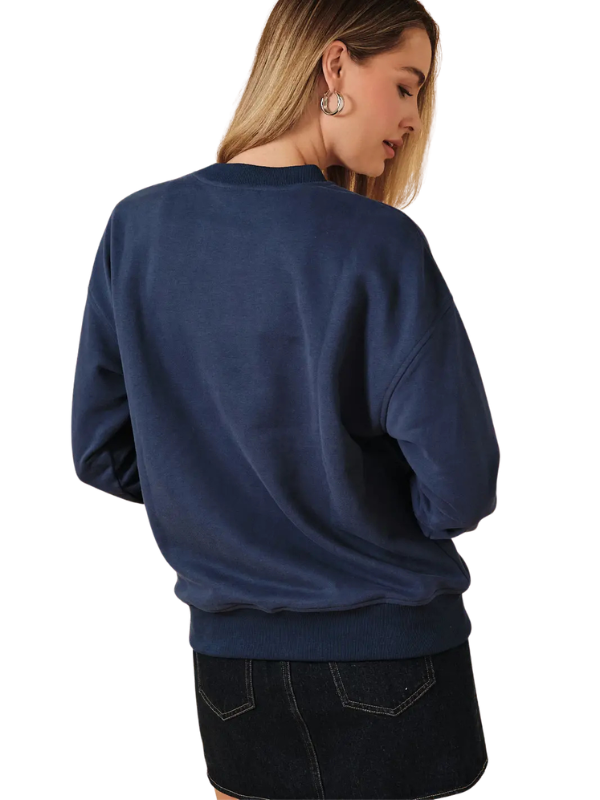 A woman shown from the back wearing a navy blue crewneck sweatshirt and a dark denim skirt against a plain white background.