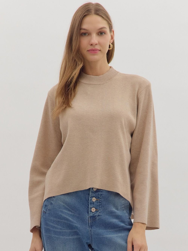 Woman wearing a beige sweater and blue jeans on a white background