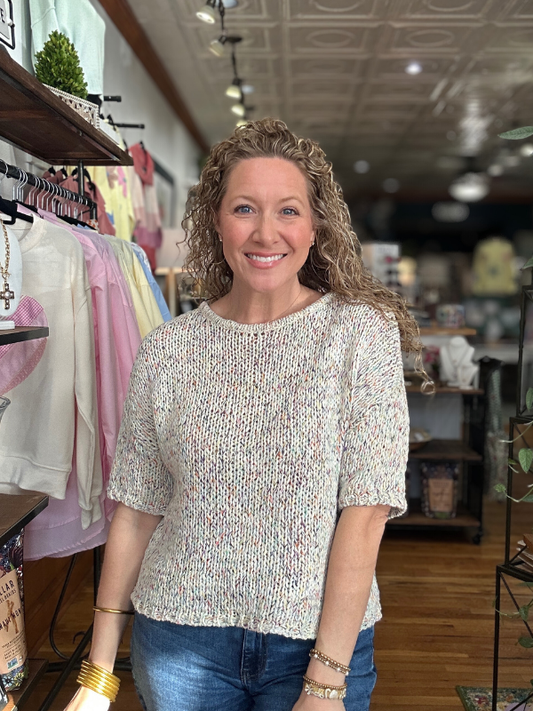 Woman standing in a store with clothing racks and products in the background