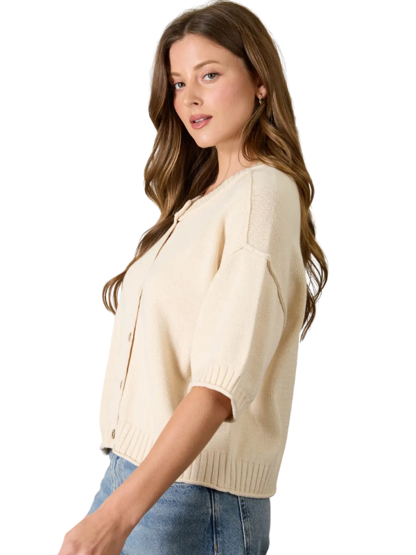 Woman wearing a beige sweater and blue jeans on a white background