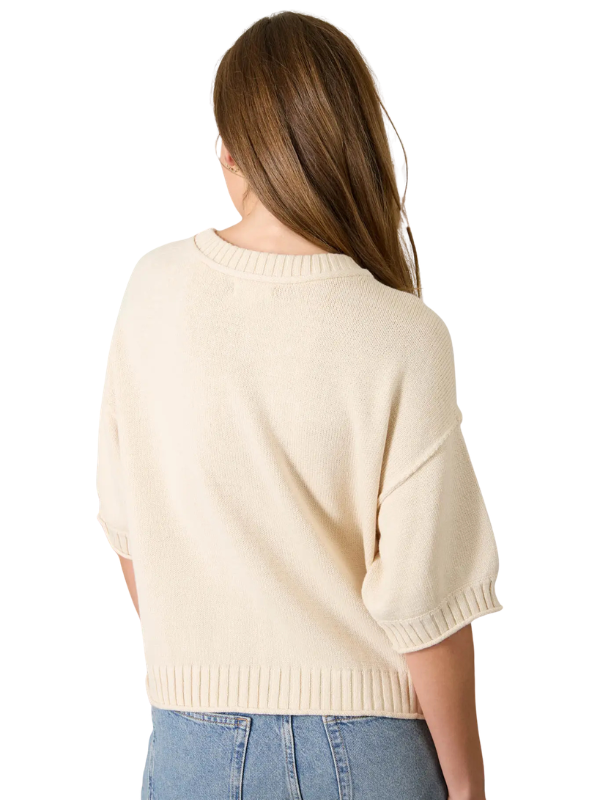 Woman wearing a cream sweater and blue jeans on a white background