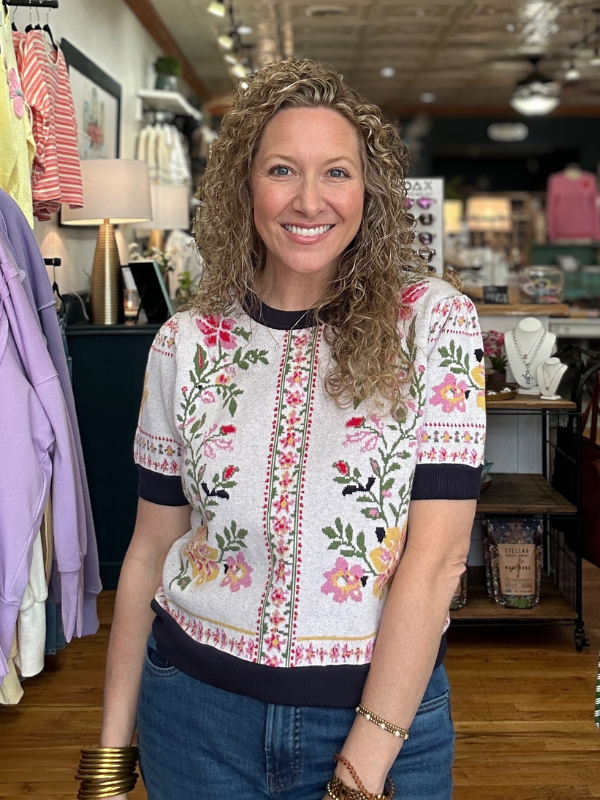 Woman wearing a floral embroidered top in a store setting