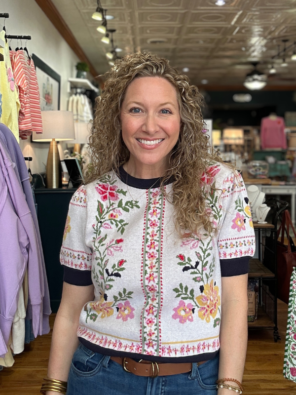 Woman wearing a floral embroidered top in a store setting