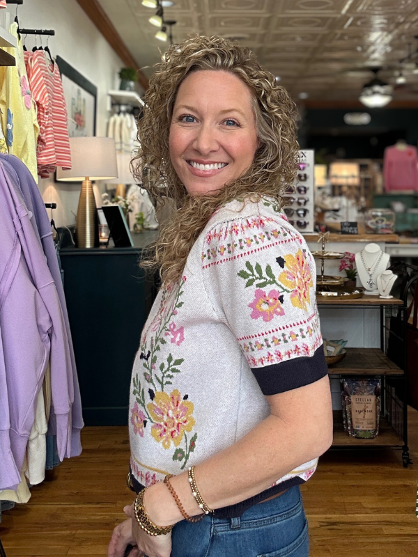 Woman wearing a floral embroidered shirt in a store setting