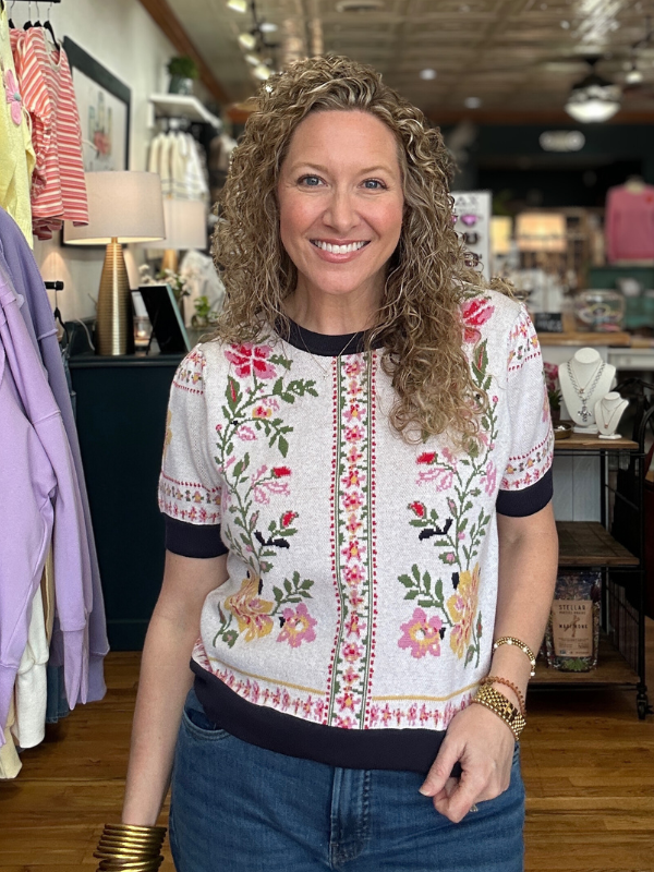 Woman wearing a floral embroidered top in a store setting