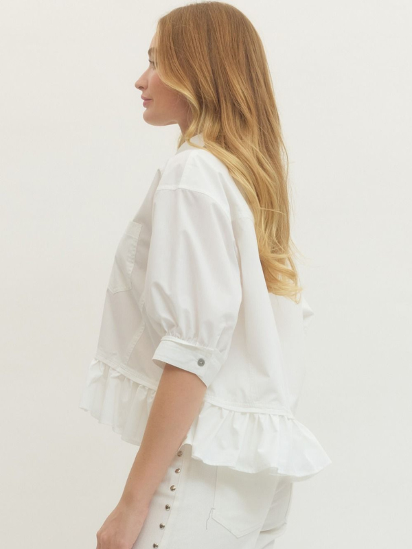 Woman wearing a white blouse with ruffled details on a plain background