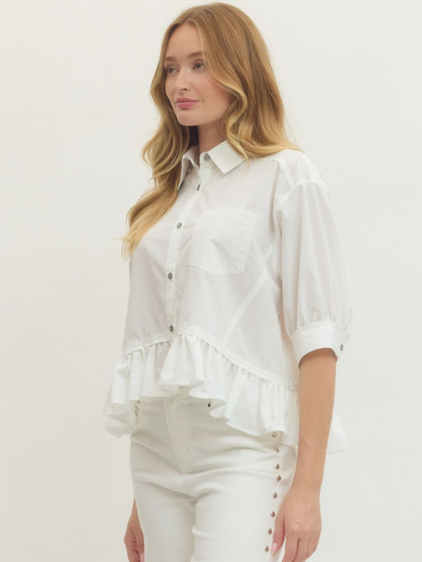Woman wearing a white blouse with ruffled details on a plain background