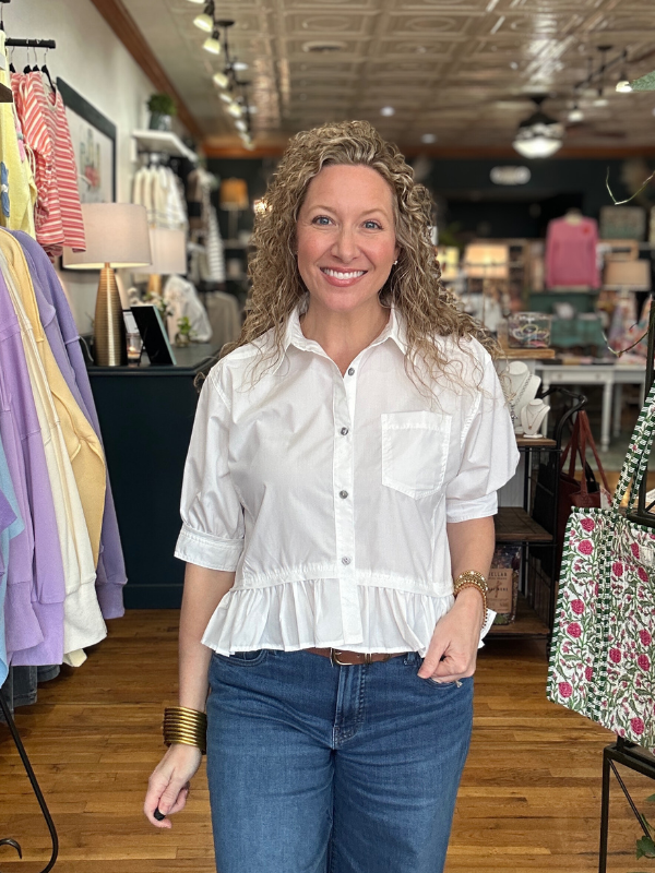 Woman wearing a white blouse and blue jeans in a clothing store.
