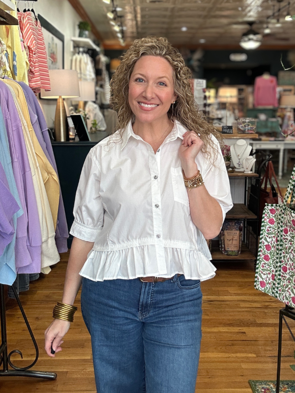 Woman wearing a white blouse and blue jeans in a clothing store.