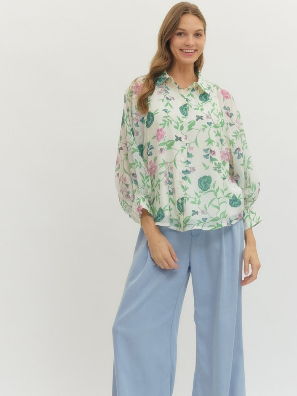 Woman wearing a floral blouse and light blue pants on a white background