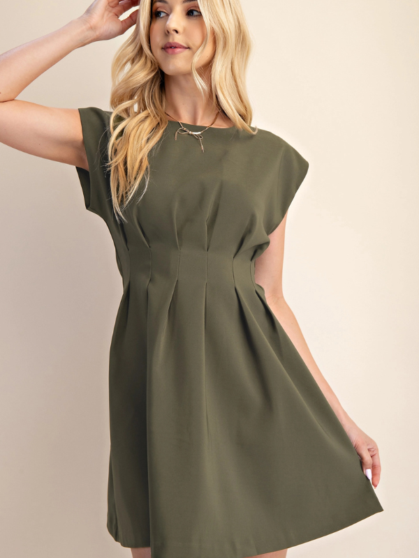 A woman wearing an olive green short-sleeve fit-and-flare dress, posing against a solid beige background.