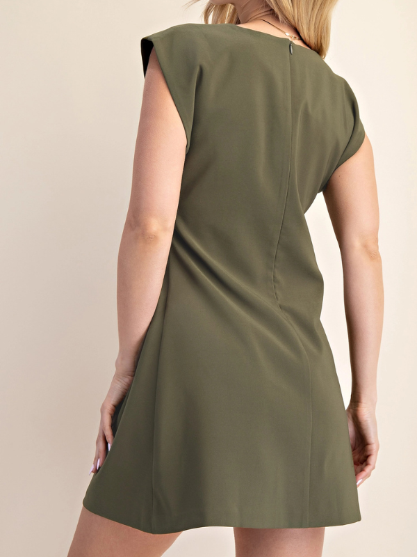 A woman wearing an olive green sleeveless shift dress, shown from the back against a plain beige background.