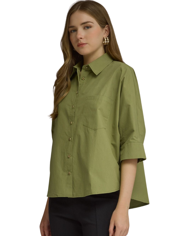 A woman wearing an olive green button-down shirt with three-quarter sleeves and black pants, photographed against a plain white background.