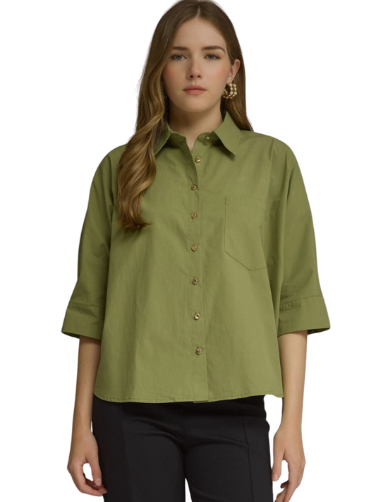 A woman wearing a sage green button-down shirt with three-quarter sleeves and black pants, photographed against a plain white background.