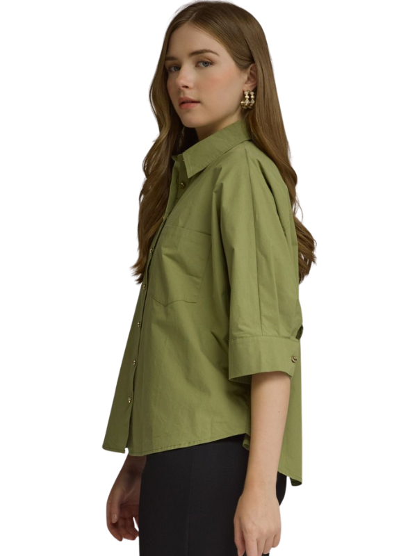 A woman wearing an olive green short-sleeve button-up shirt with black pants, shown from a side profile against a plain white background.